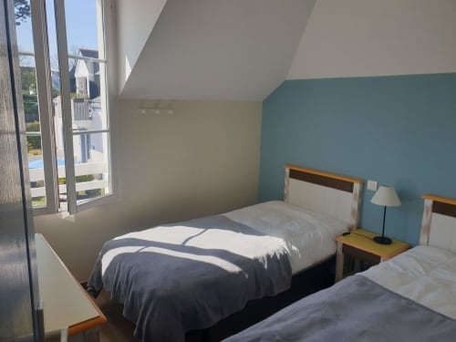 Chambre mansardée lumineuse aux Locations Loc'Maria, Belle Île en Mer, avec lits jumeaux, mur turquoise et vue sur la mer