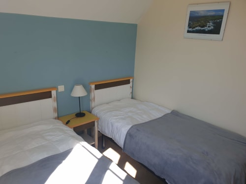 Chambre twin avec vue sur mer à Locations Loc'Maria, Belle Île en Mer, mur d'accent bleu et photo de paysage côtier