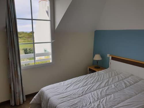 Chambre moderne avec mur d'accent couleur canard et literie blanche donnant sur les champs verdoyants de Loc'Maria, Belle Île-en-Mer