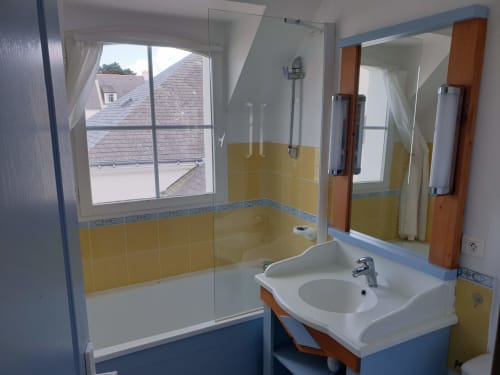Salle de bain moderne aux carrelages jaunes et bleus, lavabo, douche et baie vitrée vue mer à Loc'Maria Belle Île-en-Mer
