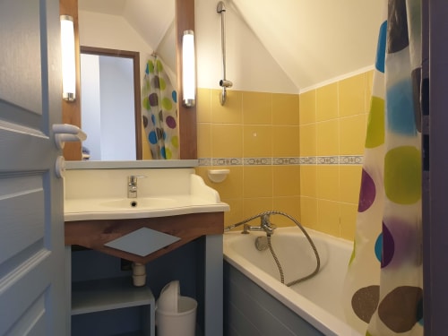 Salle de bains moderne aux carrelages jaune vif, vasque, baignoire et rideau de douche coloré de l'appartement Locmaria