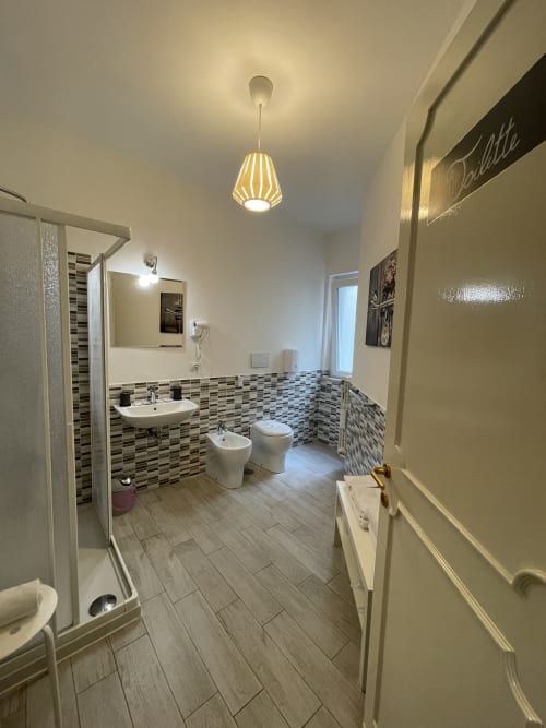 Elengance Room | Trastevere Sweet Rest, Roma. Camera tripla con balcone dotata di bagno privato esterno, prodotti da bagno, bidet, doccia, asciugamani, asciugacapelli, cucina, lavatrice, zona pranzo, zona soggiorno, TV a schermo piatto, vista cortile interno.