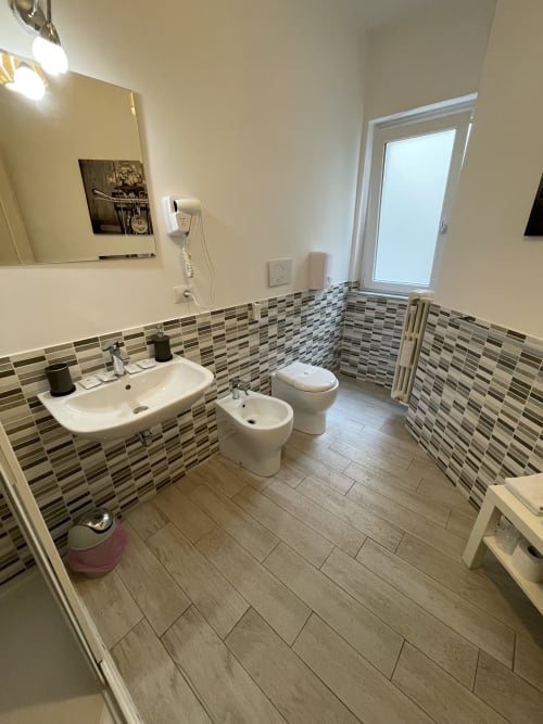 Elengance Room | Trastevere Sweet Rest, Roma. Camera tripla con balcone dotata di bagno privato esterno, prodotti da bagno, bidet, doccia, asciugamani, asciugacapelli, cucina, lavatrice, zona pranzo, zona soggiorno, TV a schermo piatto, vista cortile interno.