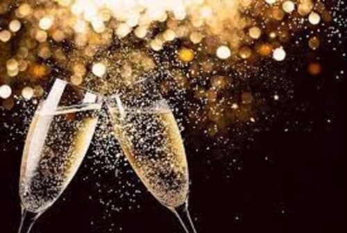Two champagne flutes toasting with golden bubbles and bokeh lights, celebrating at Locations Loc'Maria in Belle Île en Mer