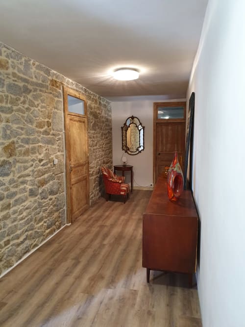 Couloir des Forges Du Lou à Jugon-les-Lacs avec murs en pierre, portes en bois et décoration vintage