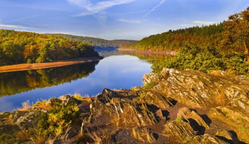 Vue pittoresque du lac en automne avec falaises rocheuses et collines boisées près du B&B Les Forges Du Lou à Jugon-les-Lacs, France