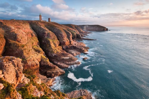 Falaises rouge dramatique et eaux turquoise de l'Atlantique avec phare près des Forges Du Lou à Lorient, Bretagne