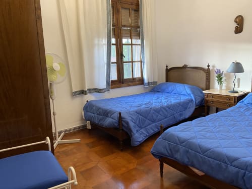 Dormitorio luminoso con dos camas acolchadas azules, muebles de madera y grandes ventanas en Chalet privado Esuri cerca de Puy Du Fou en Argés