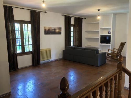Salón moderno con sofá oscuro, pisos de baldosa terracota y amplios ventanales en Chalets Junto A Puy Du Fou, Argés España