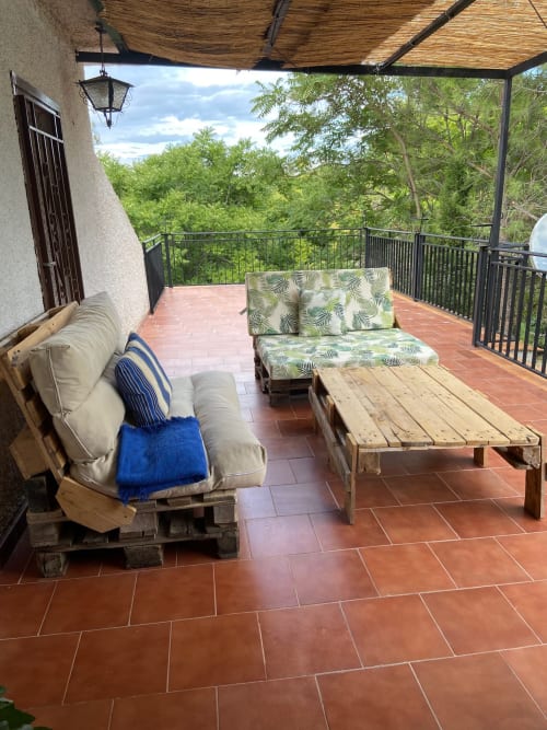 Terraza cubierta con muebles rústicos de pallets con vistas a las montañas boscosasen Chalet privado Esuri cerca de Puy Du Fou, Argés España