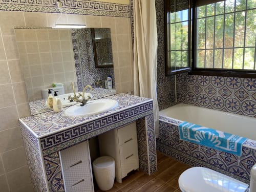 Elegante baño en los Chalets Junto A Puy Du Fou con azulejos azules estampados, lavabo, bañera y vistas a las montañas