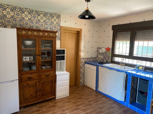 Cocina equipada en Chalet Dani con armarios de madera, encimera azul y azulejos estampados cerca del Puy du Fou