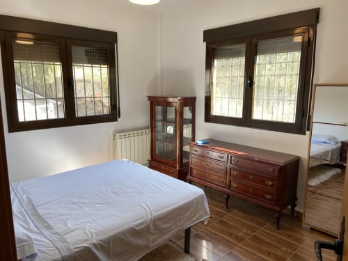 Amplio dormitorio en Chalet Dani cerca del Puy du Fou con cama, muebles de madera, ventanas con vistas a la montaña y suelo de baldosas