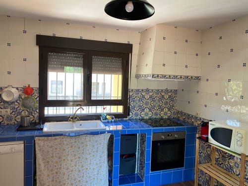 Cocina moderna con encimeras de azulejos azules y salpicadero decorativo con patrón azul en la casa rural Argés