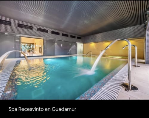 Piscina interior de spa con agua turquesa y barandillas blancas en Chalets Junto A Puy Du Fou, Argés