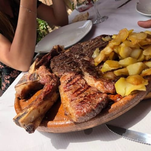 Filete a la parrilla con papas fritas crujientes servido en el restaurante Chalets Junto A Puy Du Fou en Argés, España