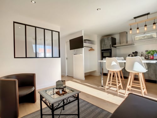 Appartement T1 moderne à la Résidence L'Hermitière avec cuisine ouverte, salle à manger, séjour avec fauteuil marron et