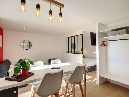 Studio moderne à la Résidence L'Hermitière avec coin repas, cuisine équipée et chambre visible à travers la vitre