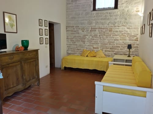 Agriturismo Ca' le Suore | Trilocale piccolo a Cagli, Marche, casa vacanze provincia Pesaro Urbino. Appartamento con terrazza, vista giardino, soggiorno con angolo cottura, camera matrimoniale, divano letto, bagno con doccia. Wifi, TV, spazio esterno, piscina con sdraio, campo da tennis, camino, ventilatore.