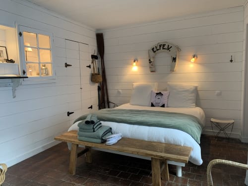 Modern bedroom at Les Filles du Bord de Mer with white shiplap walls, green bedding, pendant lights, and nautical decor