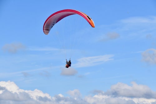 Parapentiste en vol au-dessus des nuages près de Valloire, France à l'hôtel Couleurs Montagne