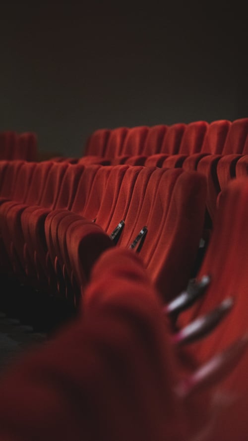 Sièges de cinéma rouges vides dans une salle obscure de l'hôtel Couleurs Montagne à Valloire