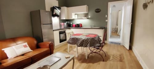 Appartement moderne à La Maison Virginie à Montargis avec séjour ouvert, cuisine, canapé orange et salle à manger donnant sur le jardin