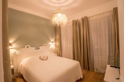 Chambre élégante à La Maison Virginie à Montargis avec lit queen-size, luminaire suspendu et rideaux donnant sur le jardin