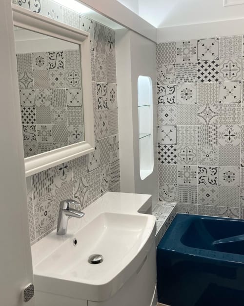 Salle de bains moderne de la Chambre d'hôtes La Maison Virginie à Montargis avec carrelage à motifs, lavabo blanc et baignoire bleue