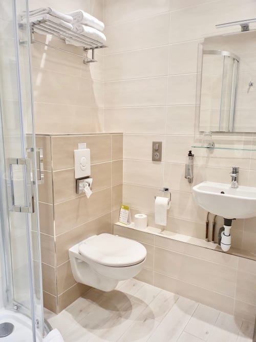 Salle de bains moderne avec douche à l'hôtel Les Cabines à Houlgate, vasque blanche, toilettes et murs carrelés