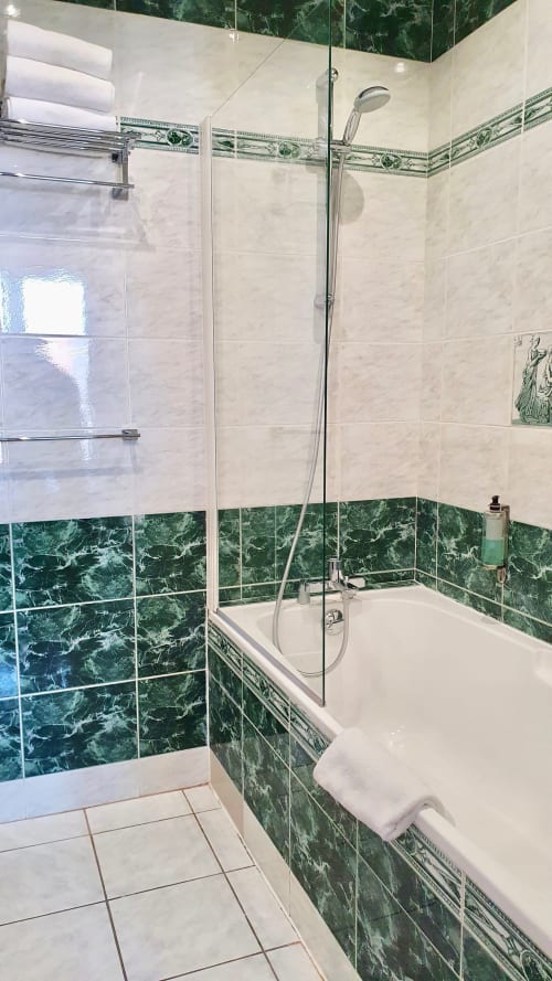 Salle de bains moderne de l'hôtel Les Cabines à Houlgate avec carrelage en marbre vert, baignoire et douche à l'italienne