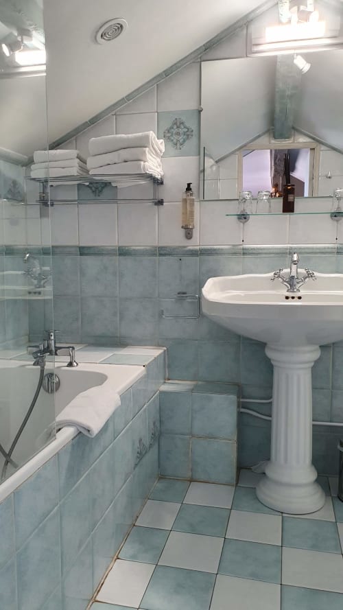 Salle de bain moderne de la suite vue mer de l'hôtel Les Cabines à Houlgate, avec lavabo sur colonne, baignoire et carrelage bleu-vert