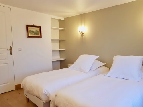Deux lits jumeaux aux draps blancs dans une chambre lumineuse de la villa de l'hôtel Les Cabines à Houlgate, avec rangements intégrés et
