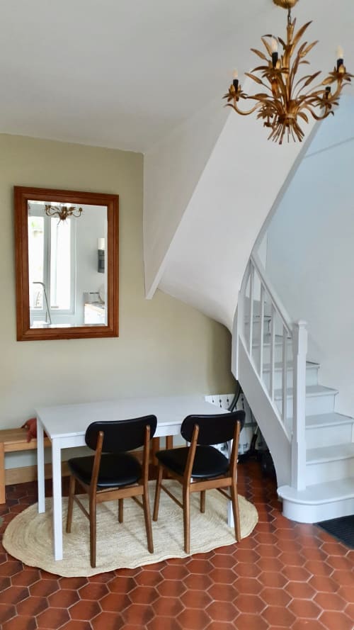 Salle à manger contemporaine de la villa Les Cabines avec table blanche, chaises en bois, escalier en spirale et lustre doré à Houlgate