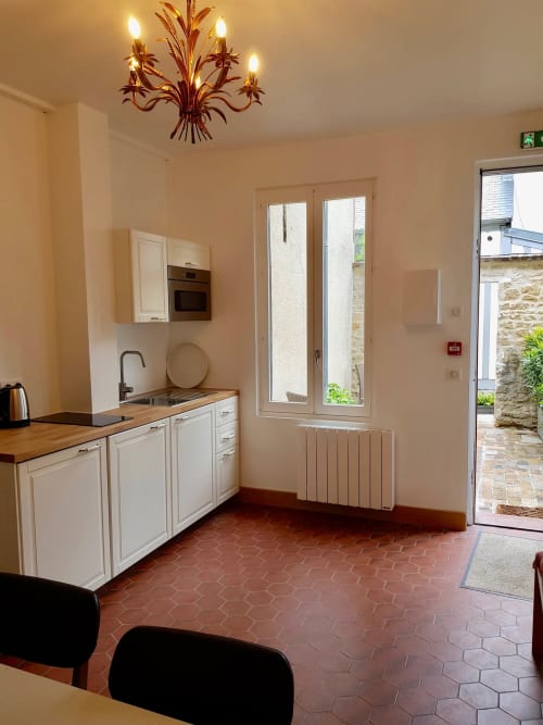 Cuisine moderne avec placards blancs, plan de travail en bois et carrelage en terre cuite dans une villa Les Cabines à Houlgate