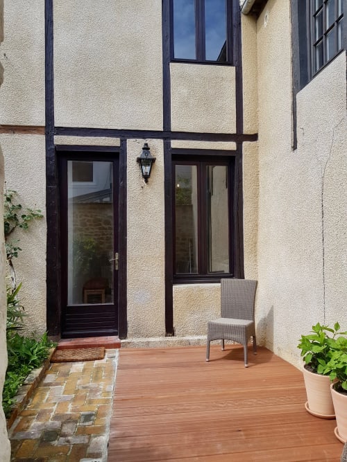 Patio cosy de la villa Les Cabines Houlgate avec terrasse bois, fauteuil en rotin et portes-fenêtres vers le jardin