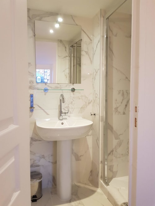Salle de bain moderne en marbre avec lavabo sur colonne et douche à la villa Les Cabines à Houlgate