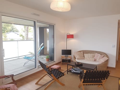 Séjour moderne de l'hôtel Mer et Maisons à La Trinité-sur-Mer avec mobilier tressé, portes-fenêtres coulissantes et vue océan
