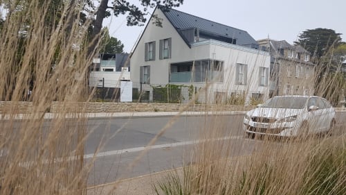 Bâtiment hôtelier blanc moderne avec toit sombre à Mer et Maisons en La Trinité sur Mer, avec voiture garée et ornements