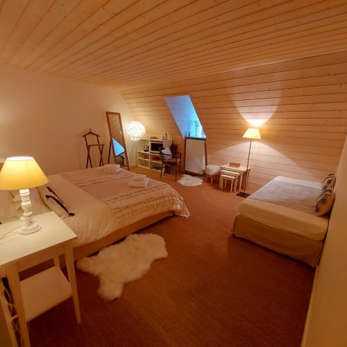 Chambre Perle, chambre mansardée du Mas De Rigoulac avec plafond en bois, lits jumeaux, bureau et éclairage chaleureux