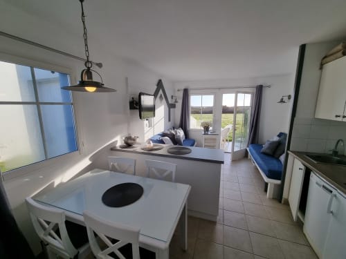 Appartement moderne ouvert avec vue mer à Belle Île en Mer, table à manger blanche, cuisine et chambre bleue