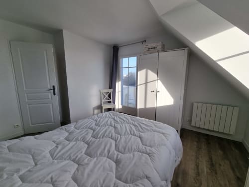 Chambre lumineuse sous les toits aux Locations Loc'Maria, Belle Île en Mer, avec penderie blanche, vue sur mer et mobilier moderne