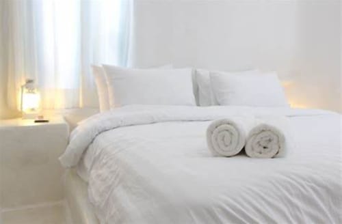 Chambre d'hôtel luxe à Belle Île en Mer avec literie blanche impeccable, serviettes roulées et lumière naturelle abondante