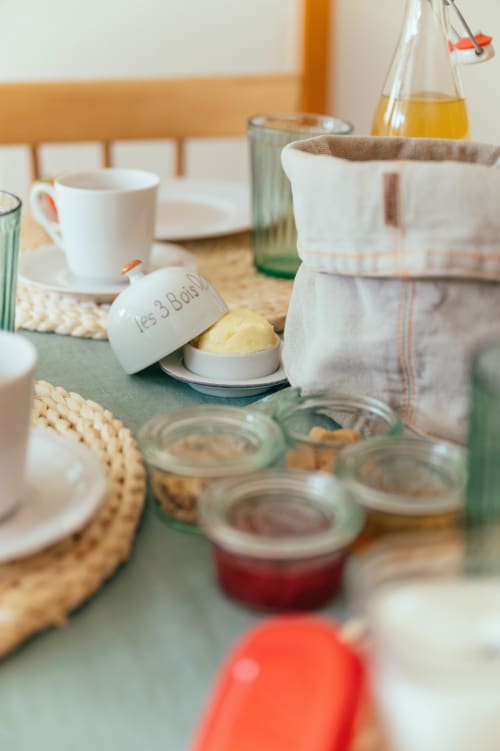 Table du petit-déjeuner aux Gites du Bulz avec beurre, confitures, tasse de café et viennoiseries à Pleyber-Christ