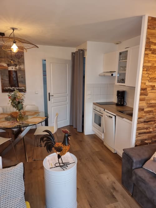 Cuisine ouverte et salle à manger de l'appartement Belle-île-en-Mer avec parquet, placards blancs et fenêtres vue mer