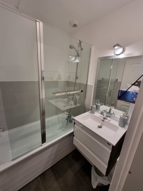 Salle de bain moderne avec douche vitrée, vasque blanche et miroir à l'appartement Locmaria, Belle Île-en-Mer