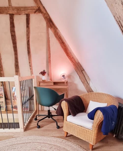 Chambre cosy sous les combles à La Dragonne avec fauteuil en osier, chaise de bureau turquoise et poutres apparentes
