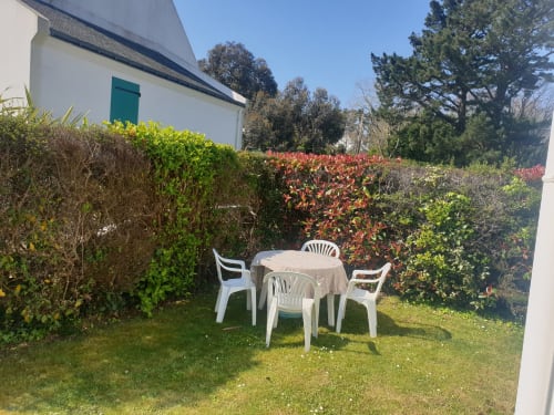Salon de jardin blanc sur la pelouse entouré de haies fleuries à Locmaria, Belle Île en Mer