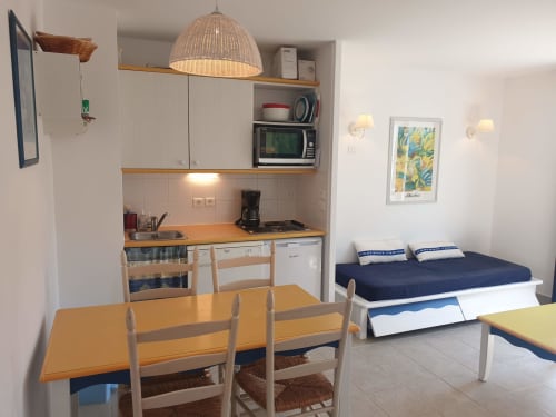 Studio à Loc'Maria, Belle Île en Mer : kitchenette, table à manger et lit avec parure bleu marine