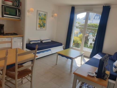 Lumineux studio à Locmaria avec lit, coin repas, kitchenette et portes donnant sur jardin à Belle Île en Mer